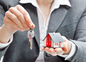 Woman holding mini house and set of keys