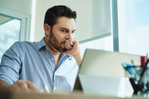 Man sitting infront of computer with worried face