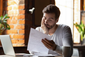 man reading a piece of paper looking concerned