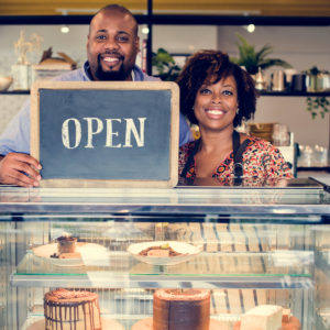 cafe owners holding an "open" sign