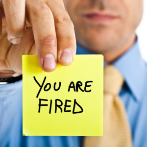 man holding "you are fired" note